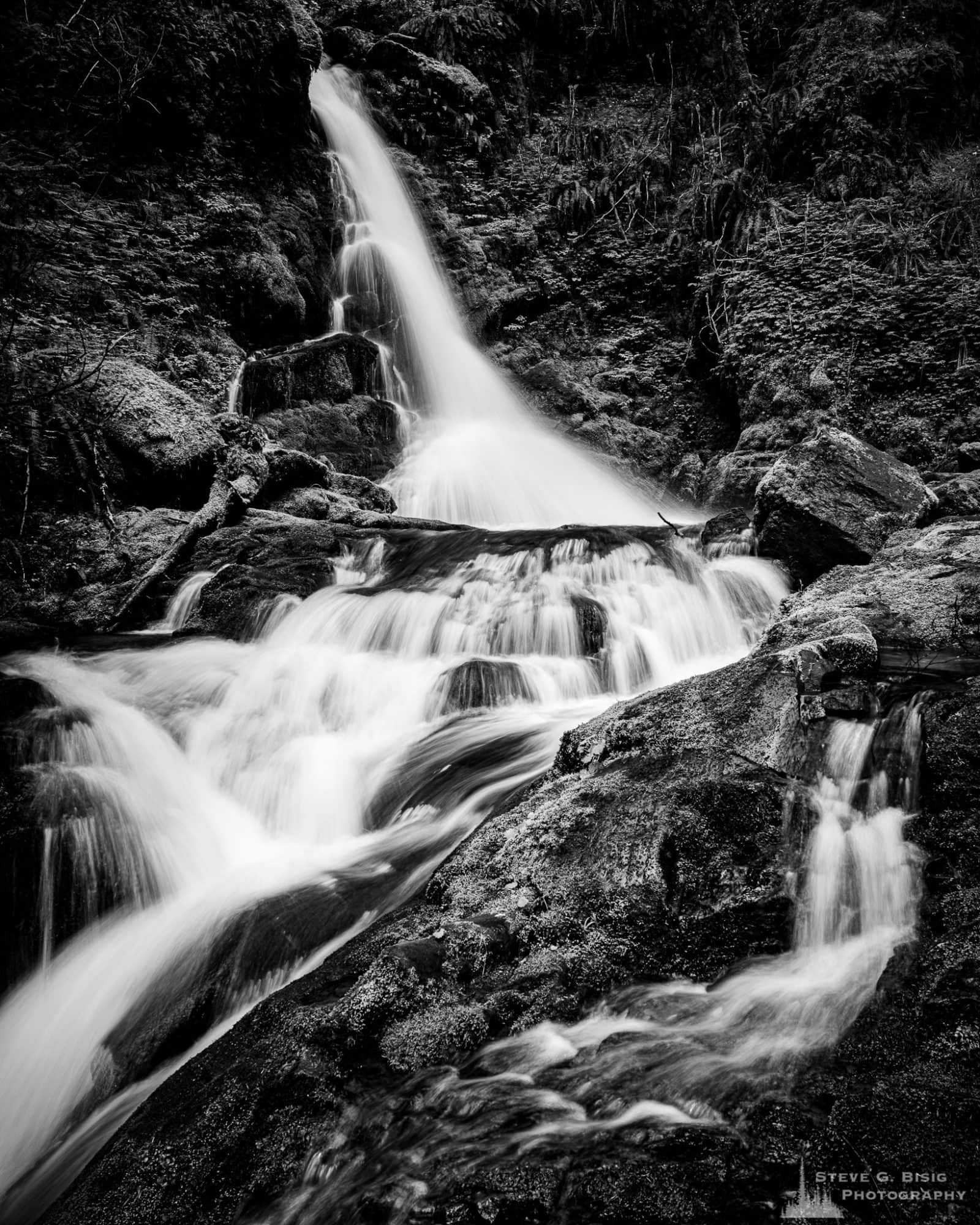 A black and white landscape photograph of a cascading waterfall found along Forest Road 52 (Skate Creek Road) in the Gifford Pinchot National Forest, Washington.