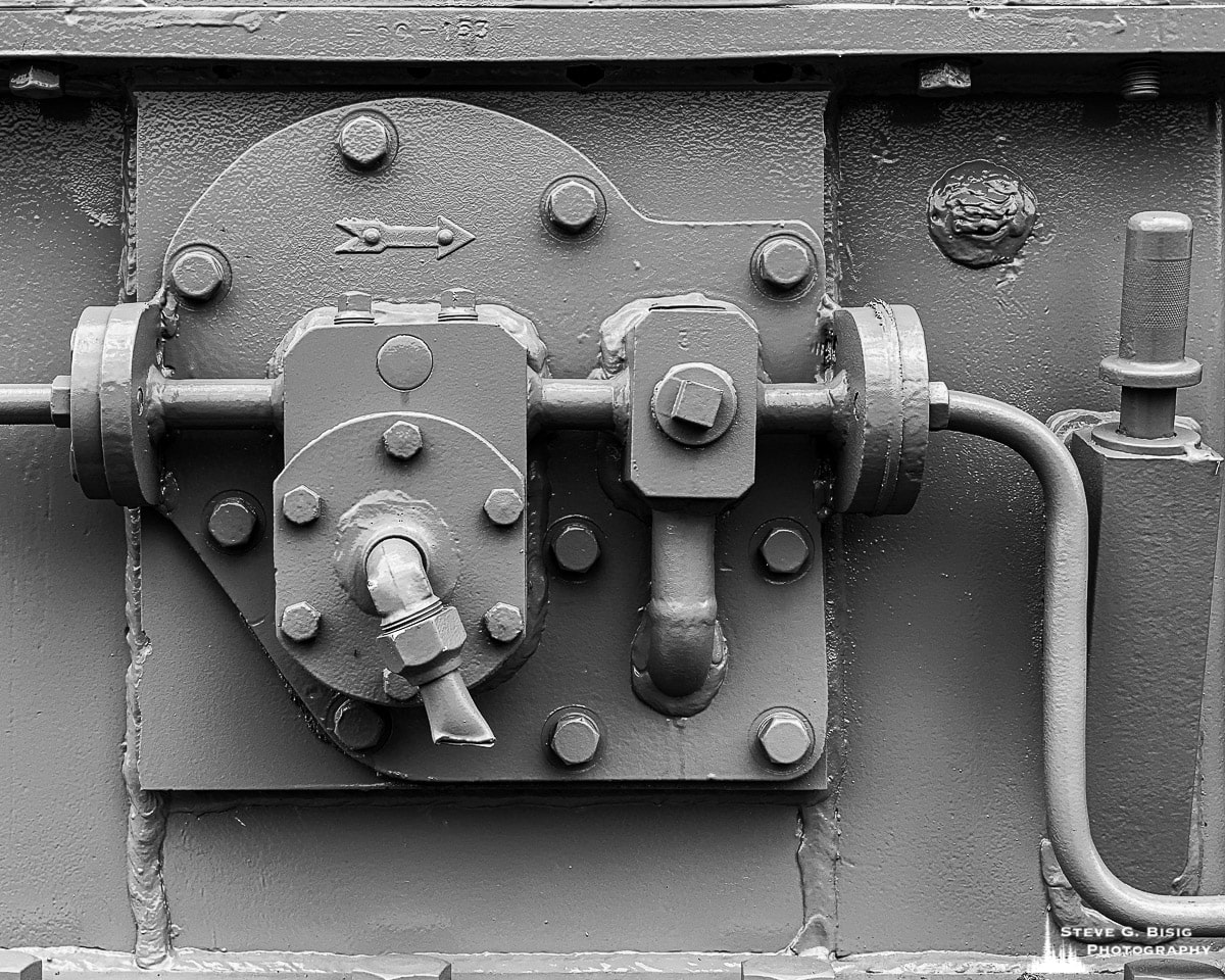A close-up black and white mobile photograph of old machinery along the historic waterfront in Astoria, Oregon.