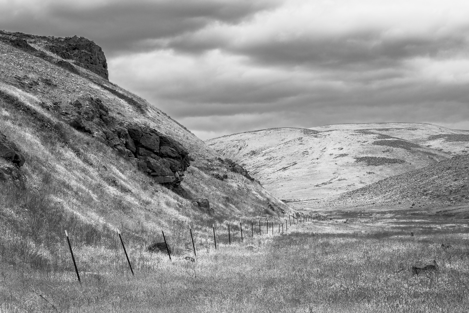 A black and white landscape photograph of a fence line running along Rocky Coulee near Vantage, Washington.